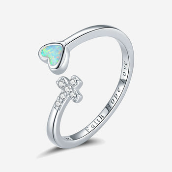 Silver ring featuring an opalescent heart and a sparkling cross, with the engraved words Faith Hope Love